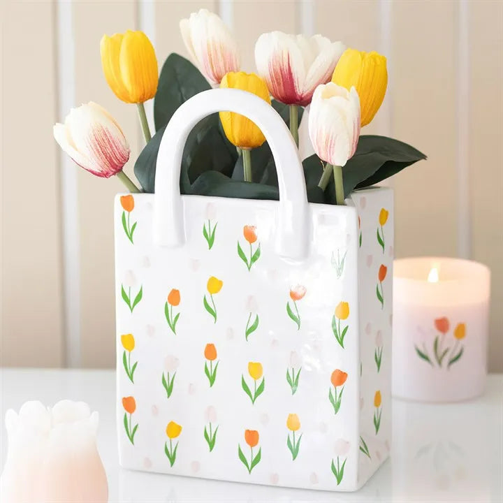 Small gift bag vase with tulip pattern containing flowers on a neutral background