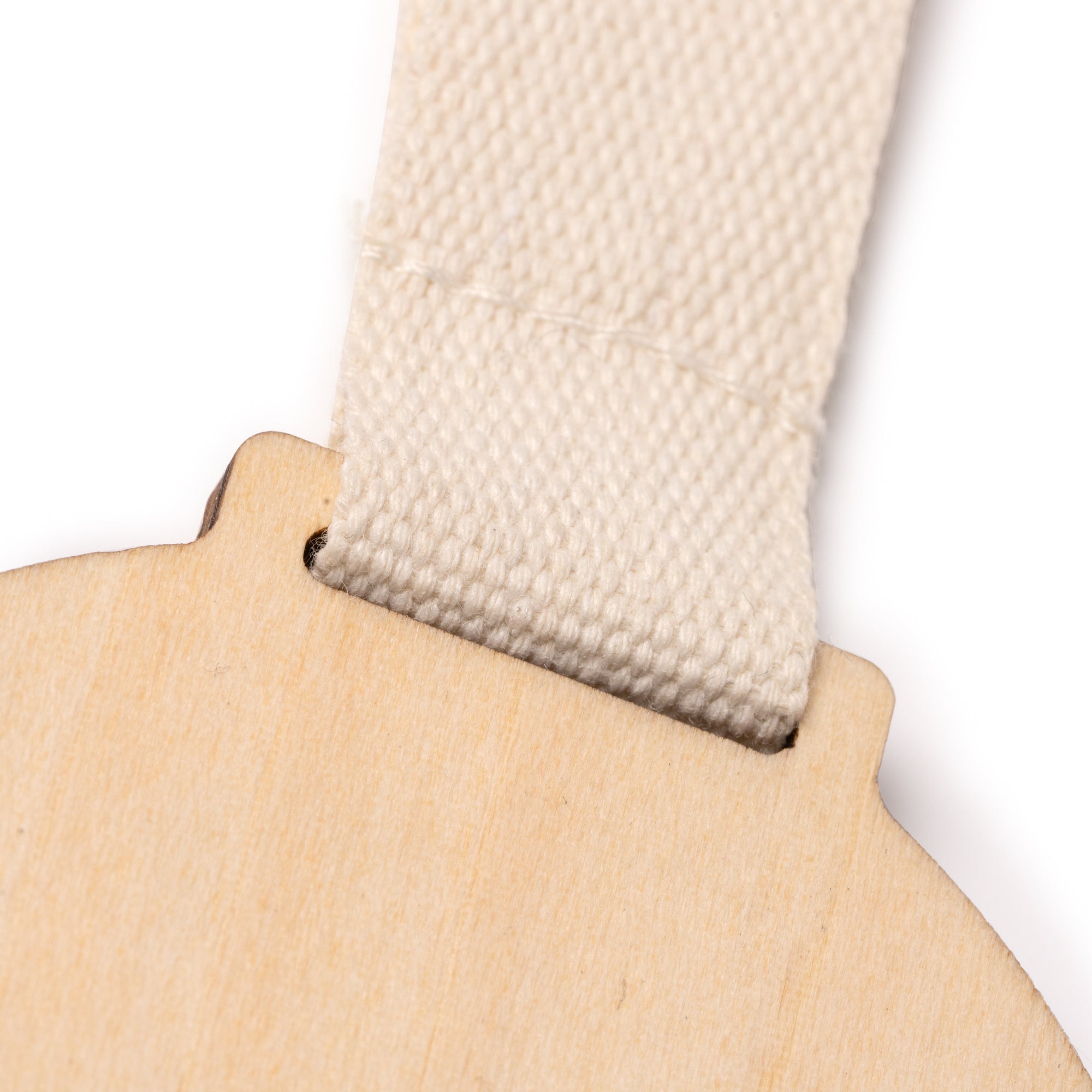 Close-up of a wooden medal with a beige fabric strap on a white background