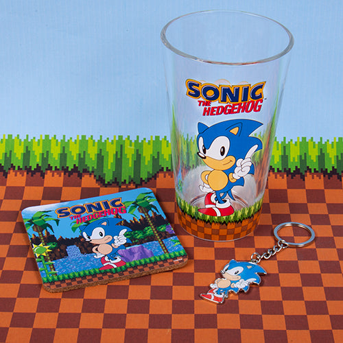 A set including a glass with Sonic the Hedgehog character design, a cork coaster with the same character, and a metal keyring featuring the hedgehog.