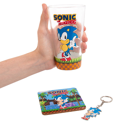 A set including a glass with Sonic the Hedgehog character design, a cork coaster with the same character, and a metal keyring featuring the hedgehog.