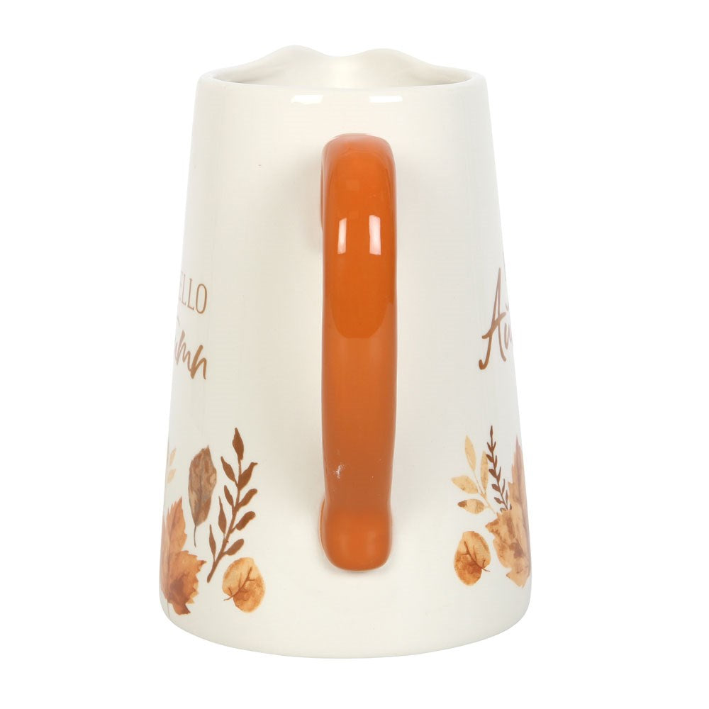 White pitcher with orange handle and autumn-themed designs on a white background