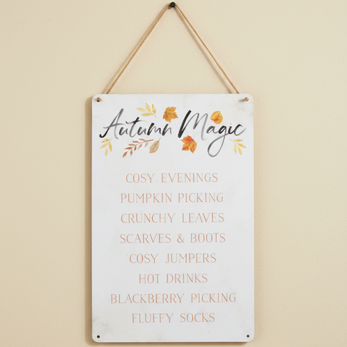 Decorative sign with 'Autumn Magic' text and fall-themed phrases on a beige wall.