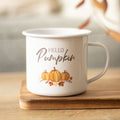 White enamel mug with 'Hello Pumpkin' text and pumpkin design on a wooden surface