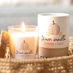 Warm vanilla scented candle with a pumpkin label on a woven surface next to its packaging