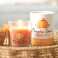 Pumpkin spice scented candle next to packaging box on a woven surface with a blurred background