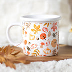 White mug with autumn-themed pattern on a wooden surface