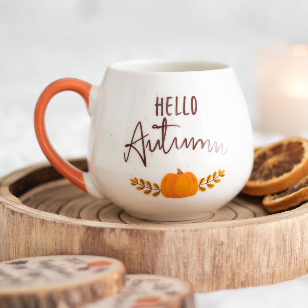 White speckled mug with 'Hello Autumn' text and pumpkin design on a wooden tray.