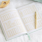 Open notebook with gold line art on a white surface with a pen.