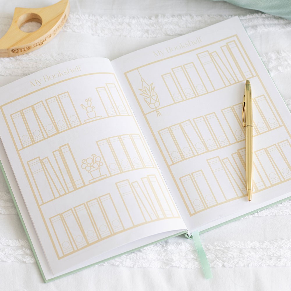 Open notebook with gold line art on a white surface with a pen.