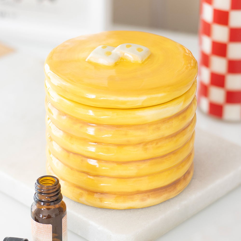 Stack of yellow pancakes oil burner with syrup on a white plate