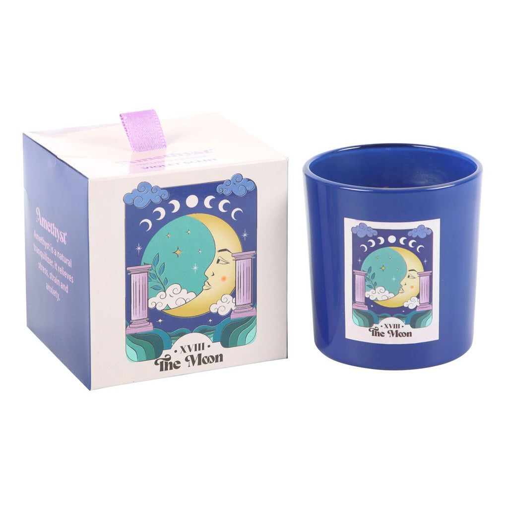 Blue candle with astrological moon design next to its packaging on a white background