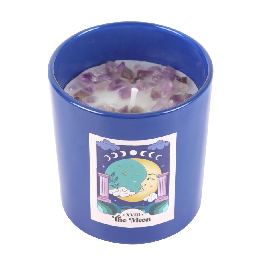 Candle in a blue glass container with a moon design on a white background