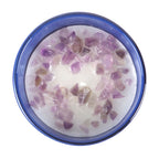 Candle with purple crystals in a blue glass on a white background