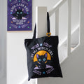 Black tote bag with a cat design and text hanging on a white staircase.