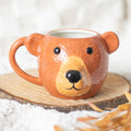 Bear-shaped mug on a wooden surface with a soft white background