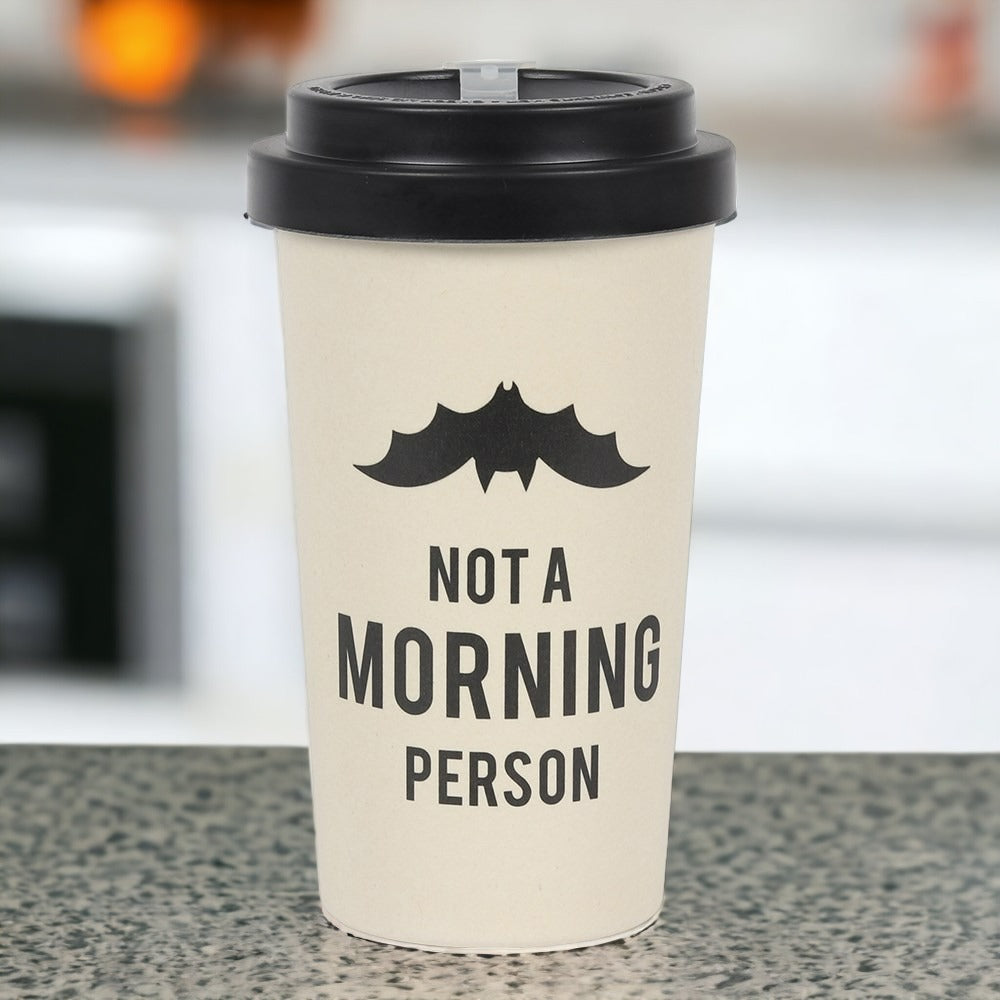 A beige travel mug with a black silicone lid and a bat silhouette design on the side, accompanied by the text 'Not a Morning Person'.