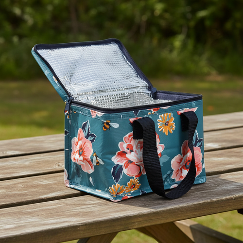 Floral and bee patterned cooler bag on a wooden table outdoors