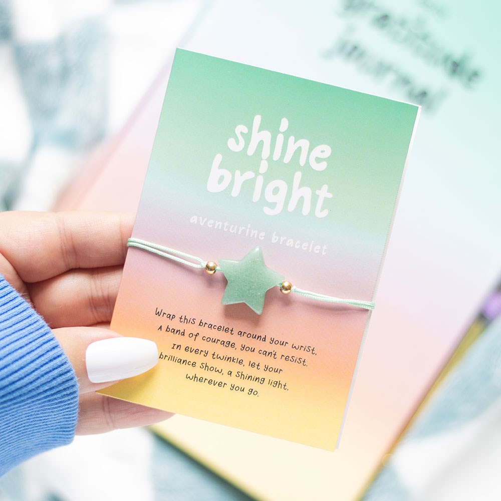 Bracelet and packaging with 'shine bright' text and a star-shaped charm, held by a hand.
