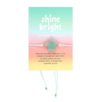 Bracelet on card packaging with 'shine bright' text on a colorful background