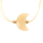 Gold crescent moon bracelet with small gold beads on a white background