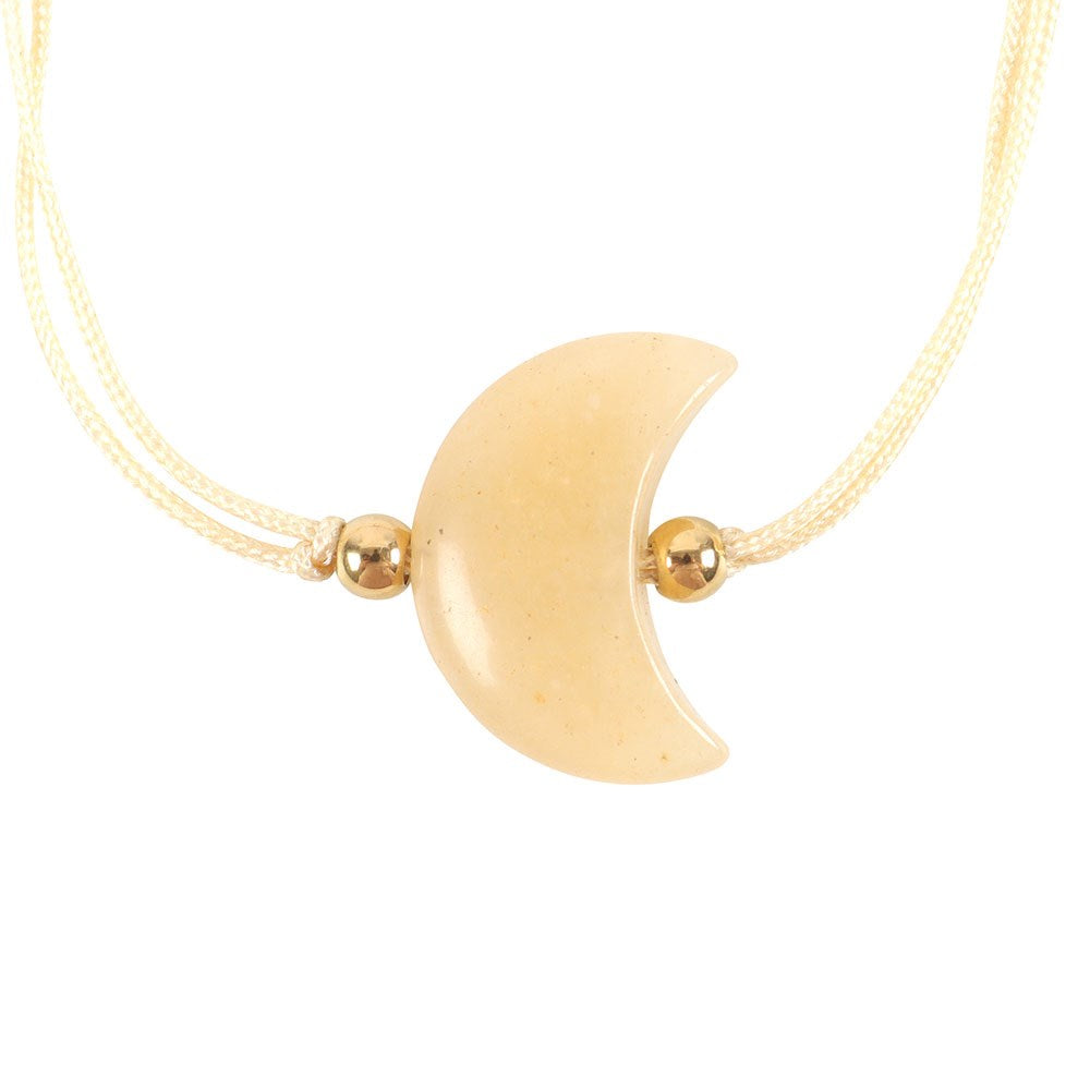 Gold crescent moon bracelet with small gold beads on a white background