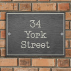 A rectangular, slate house sign with white engraved text displaying the address '34 York Street'.