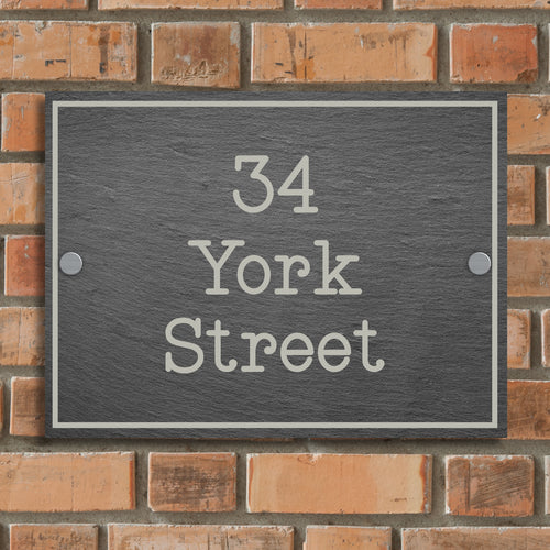 A rectangular, slate house sign with white engraved text displaying the address '34 York Street'.