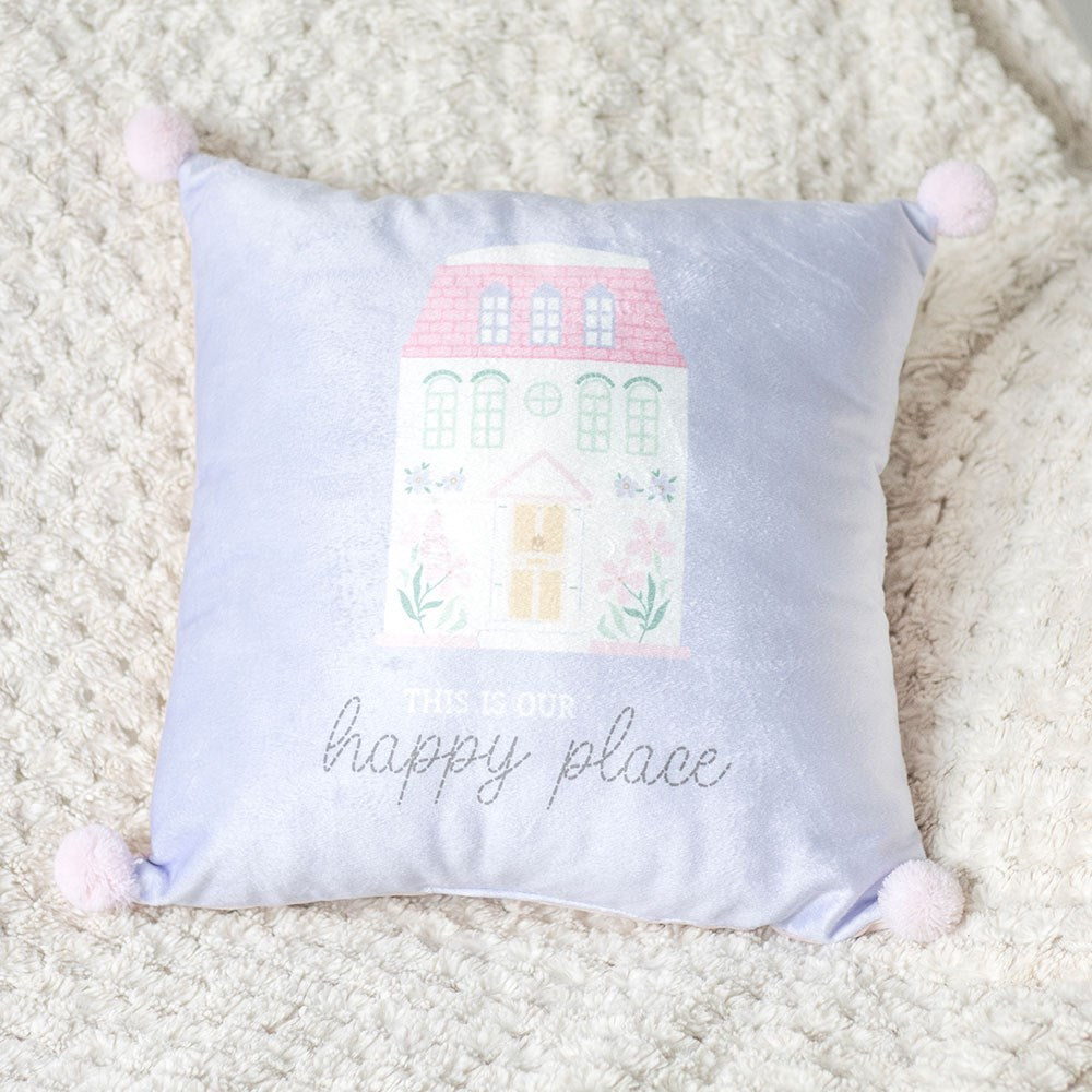 Decorative cushion with a house illustration and 'this is our happy place' text on a soft surface.