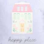close up of cushion .Pastel coloured house illustration with 'This is our happy place' text on a light purple background