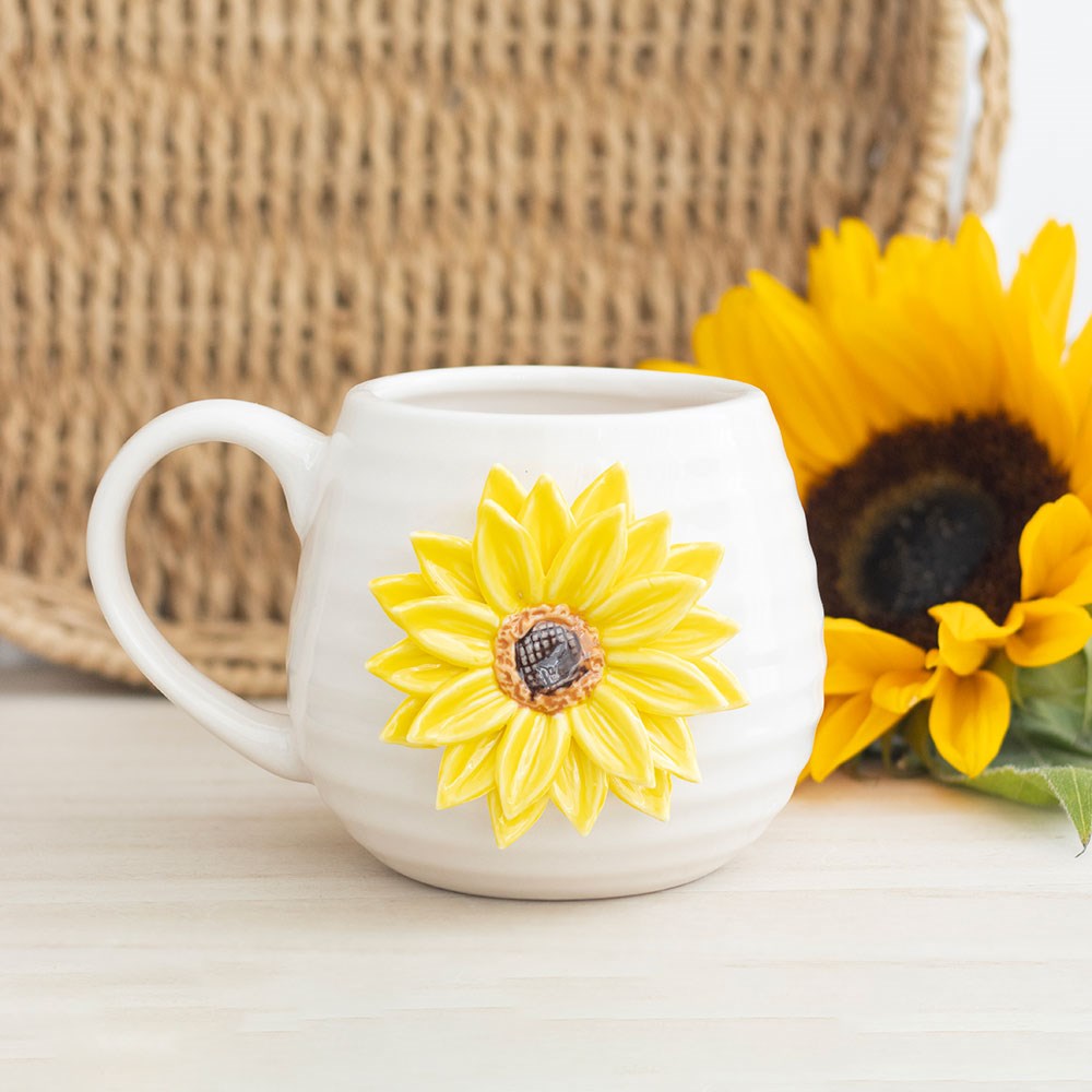 White ribbed mug with a 3D yellow sunflower design on a white surface with a woven basket in the background.