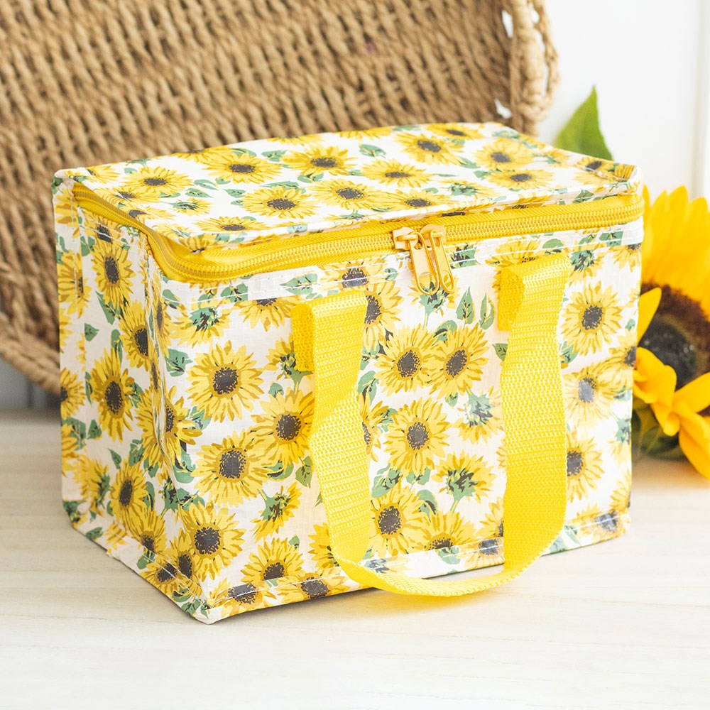 Yellow sunflower insulated lunch bag on a light surface with a woven basket in the background.