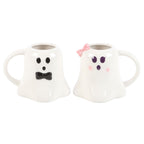 Two ghost-shaped mugs, one with a bow tie and the other with a pink bow, on a white background.