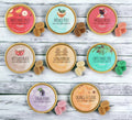 A collection of eight eco-friendly soy wax melts in various Christmas-themed fragrances, such as Orange & Clove, Sugar Plum, and Christmas Tree, arranged in an alternating pattern in eco-friendly aluminium tins.