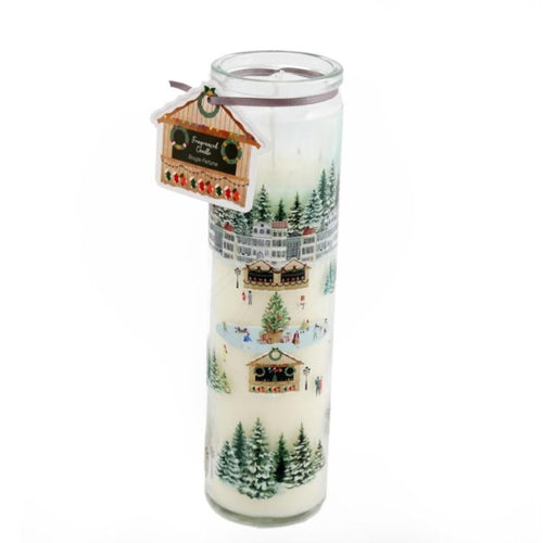 A cylindrical candle with a Christmas village design, featuring buildings and trees, predominantly white background.