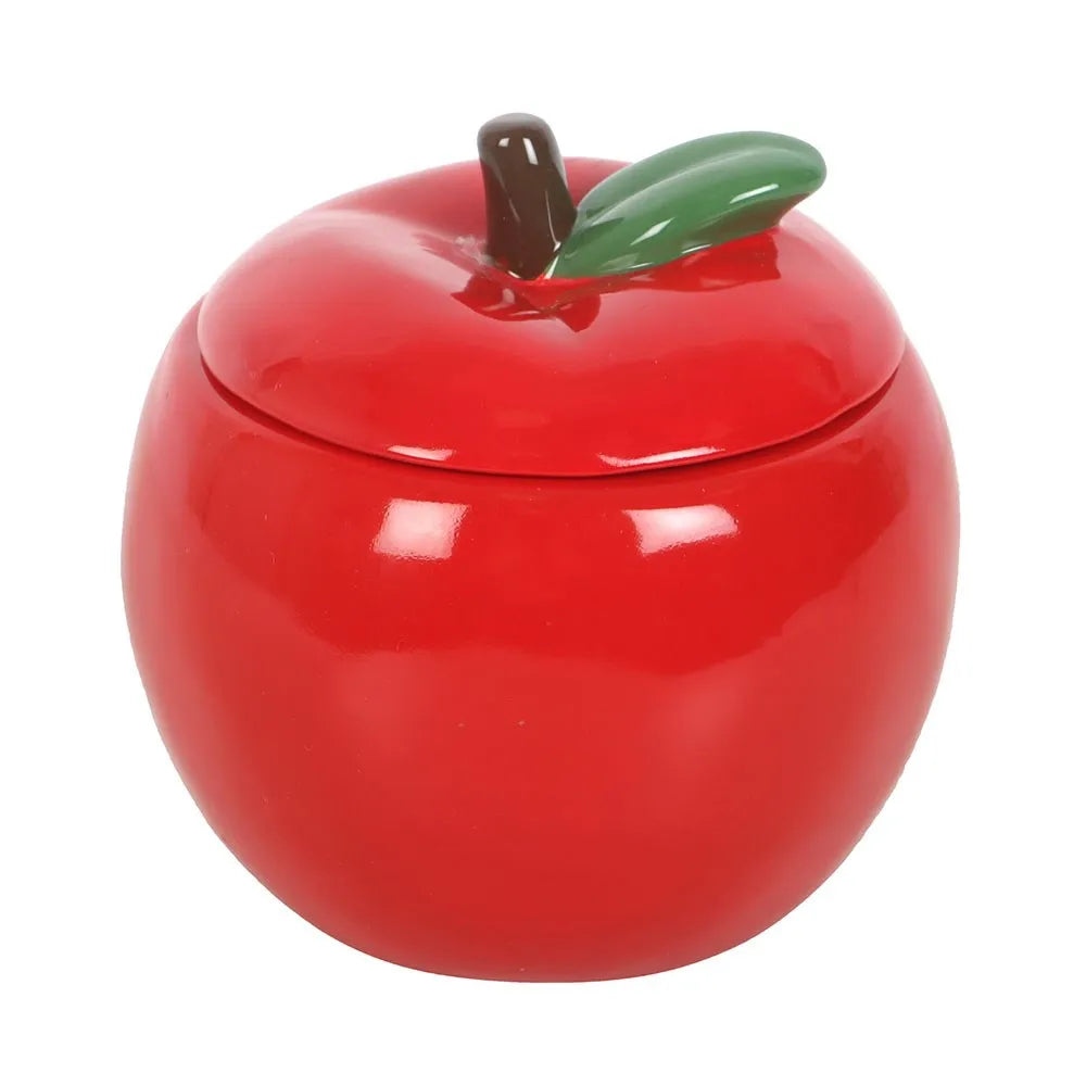 Red apple-shaped ceramic candle jar with a green leaf on a white background