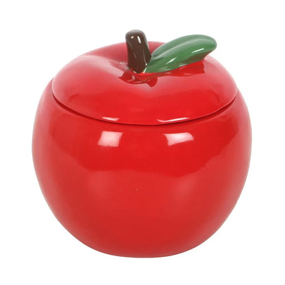 Red apple-shaped ceramic candle jar with a green leaf on a white background