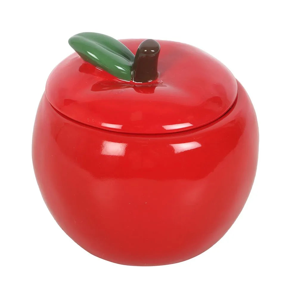 Red apple-shaped ceramic candle jar with a green leaf on a white background