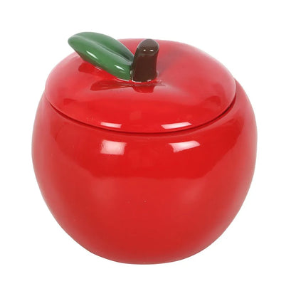 Red apple-shaped ceramic candle jar with a green leaf on a white background
