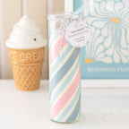 Striped glass candle with a tag in front of an ice cream cone and floral book