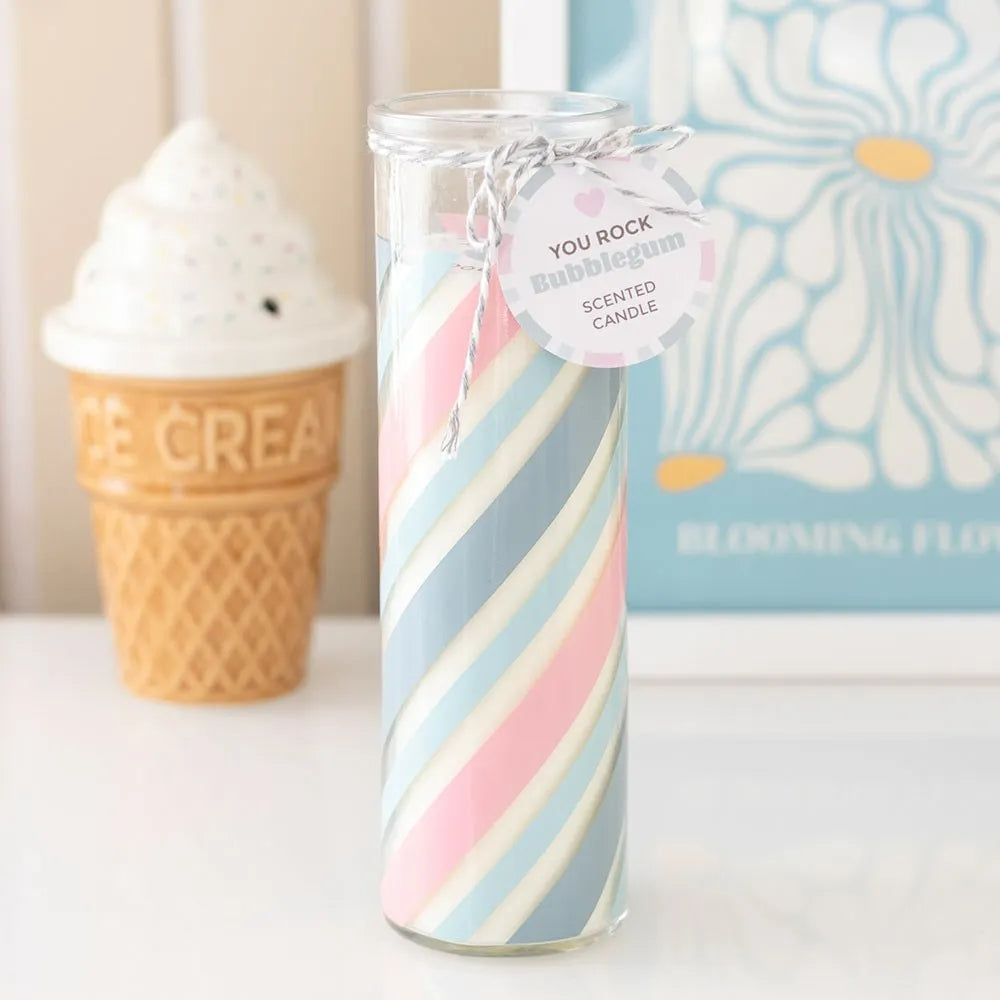Striped glass candle with a tag in front of an ice cream cone and floral book