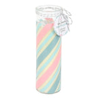 Glass tube candle with pastel pink and blue striped candle and decorative tag on a white background