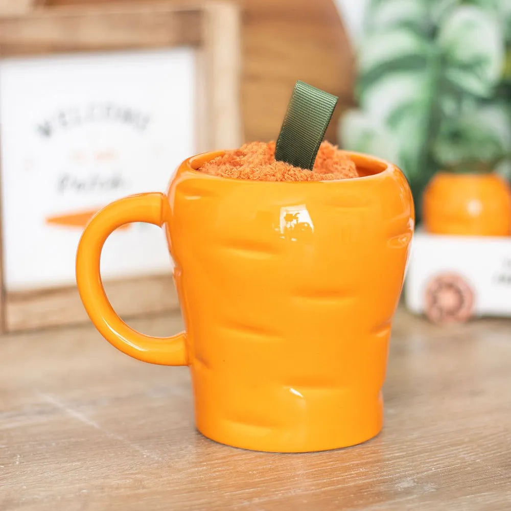 Orange carrot shaped mug with fluffy cosy socks on a wooden surface