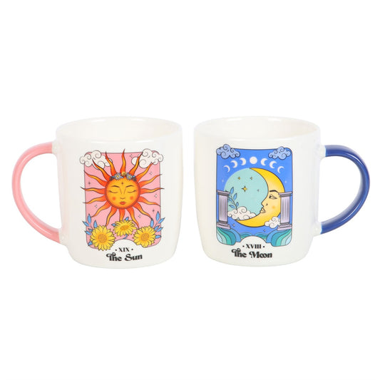 Two mugs with celestial designs, one featuring the sun and the other the moon, on a white background.