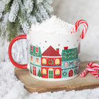 Mug with Christmas village design filled with hot chocolate and whipped cream, surrounded by candy canes and a snowy background.