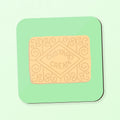A square coaster featuring a custard cream biscuit on a green background