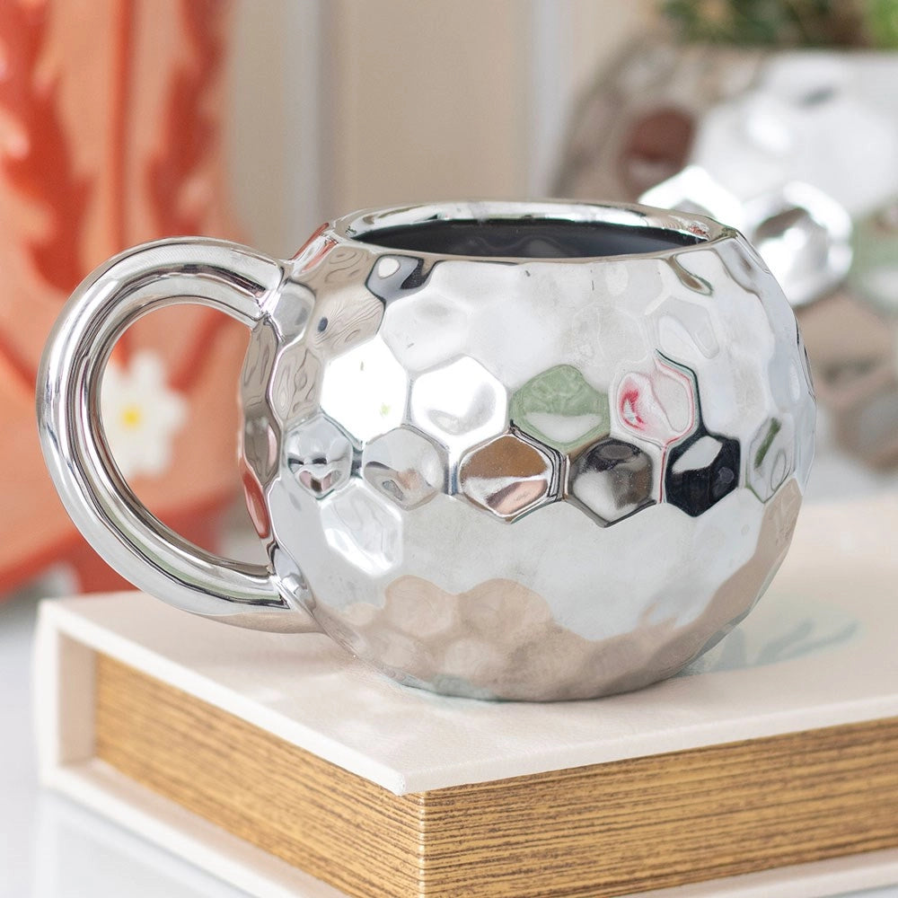 Silver disco ball mug on a wooden surface with a blurred background