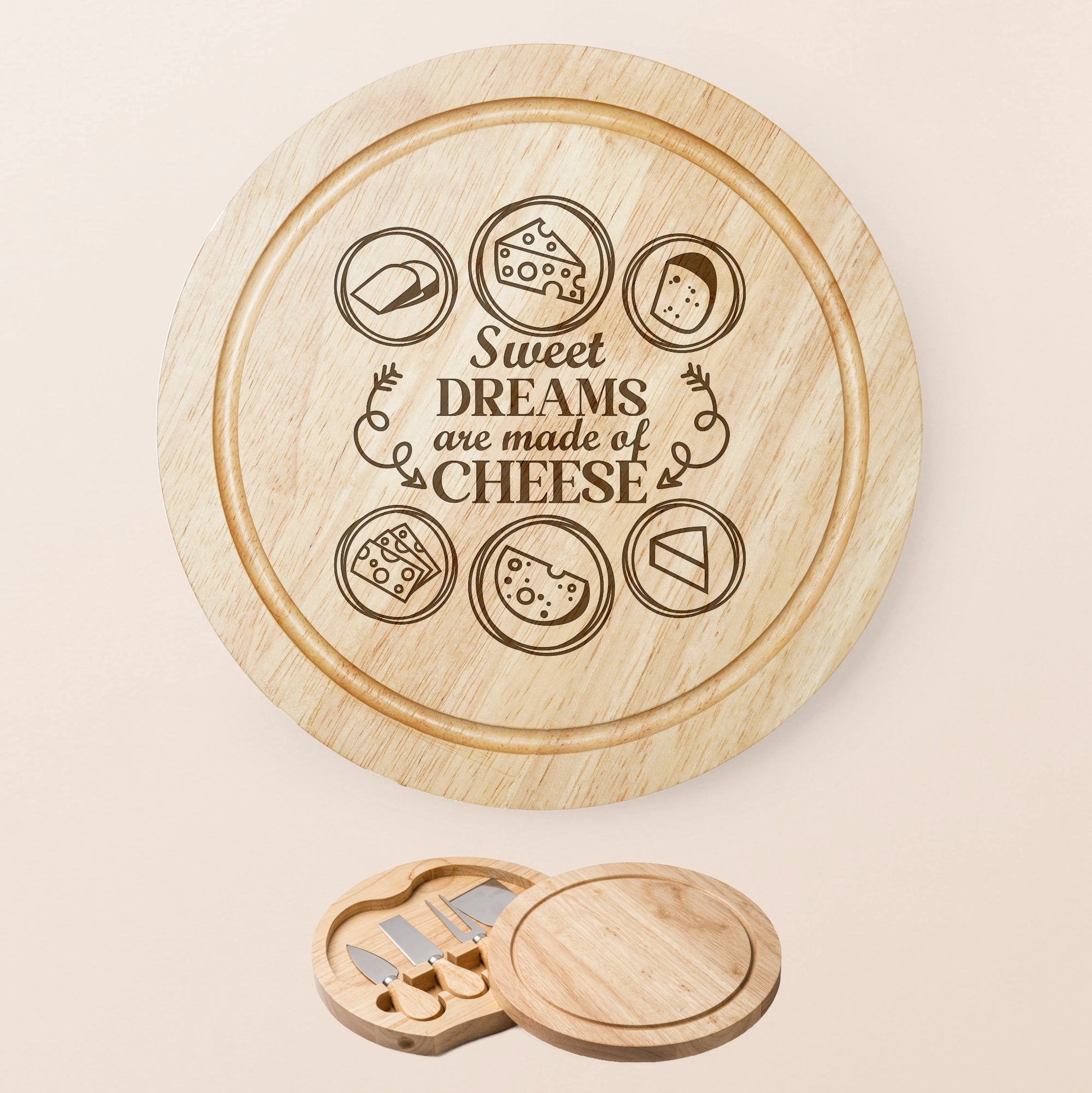 A round wooden cheese board set shown on a pale beige background. The main board is engraved with cheese icons and the phrase “Sweet Dreams are made of Cheese.
