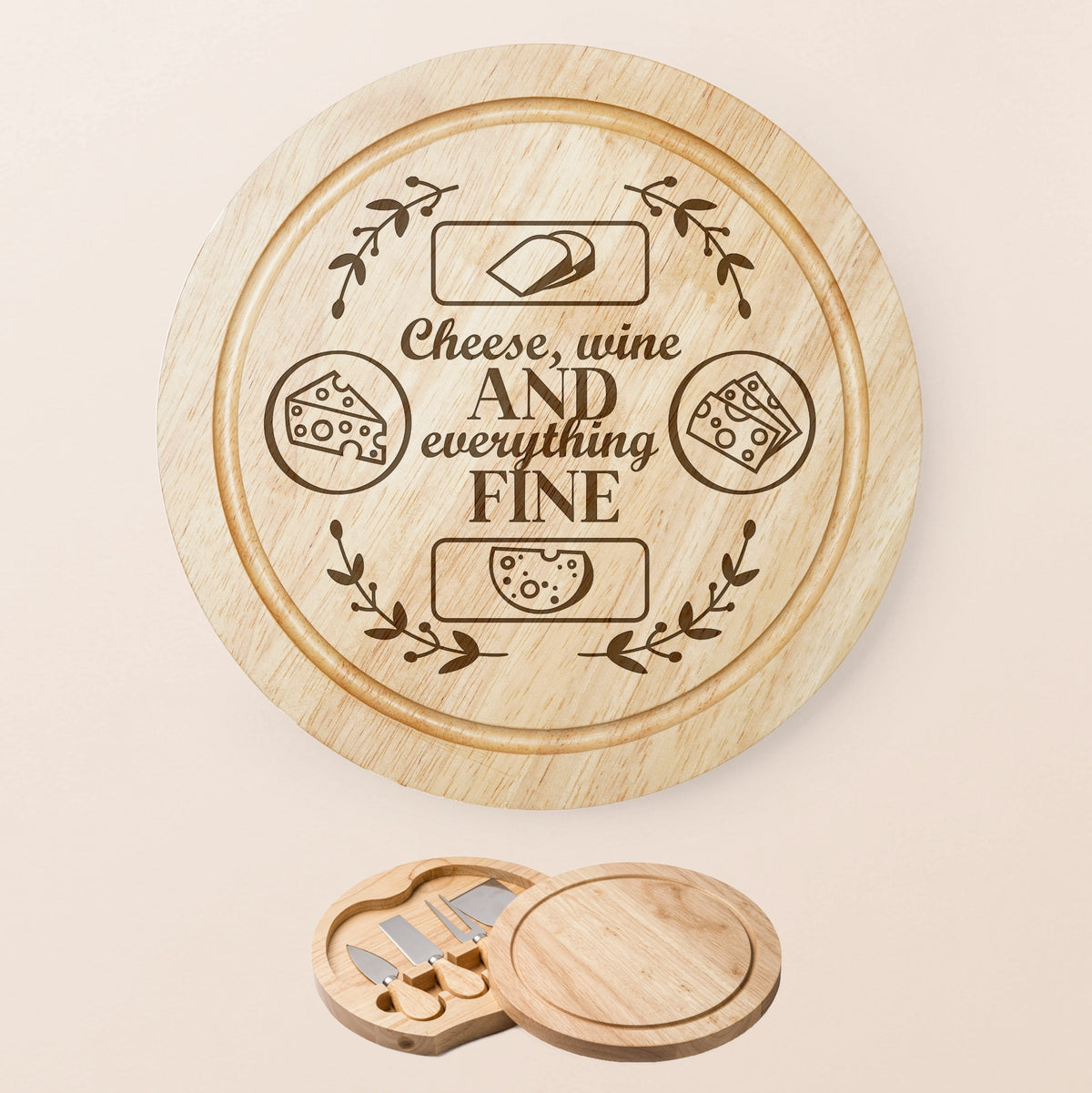 A round wooden cheese board set with engraved text reading 'Cheese, wine AND everything FINE' and cheese illustrations, shown on a light beige background. A smaller inset at the bottom shows the matching wooden cheese knives and board lid.
