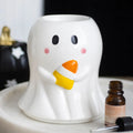 A ceramic oil burner shaped like a ghost holding a candy corn