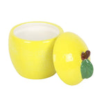 Yellow ceramic lemon-shaped container candle with a lid on a white background